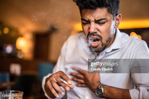 homme fumant une cigarette dans le bar et toussant. - bar tender photos et images de collection