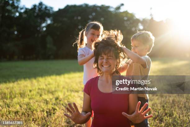 children in park messing up their mom's hair - chaos stock-fotos und bilder