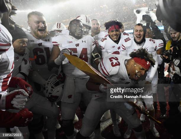 Jonathan Taylor of the Wisconsin Badgers celebrates defeating the Minnesota Golden Gophers by using the Paul Bunyan Axe trophy after the game at TCF...