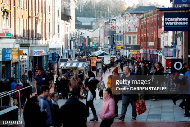 Shoppers walk in the town centre of Walsall on November 29, 2019. - With its deserted streets and closed shops, the centre of Walsall bears witness...