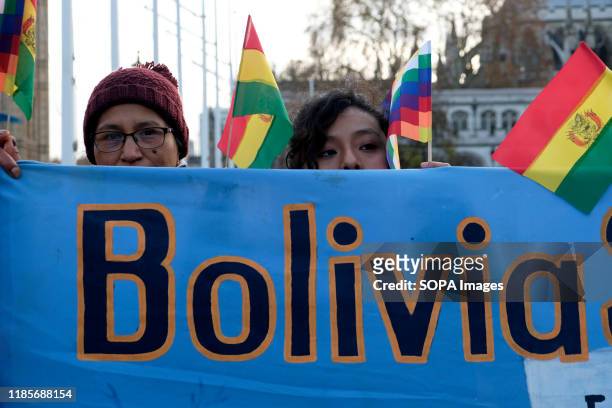 Protesters hold a banner, Bolivian and Wiphala flags during the rally. People gathered outside Downing Street to raise their voices against the coup...