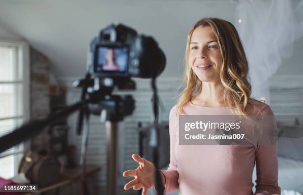 gelukkige vrouwelijke vlogger live streamen vanuit de woonkamer - vinyl film stockfoto's en -beelden