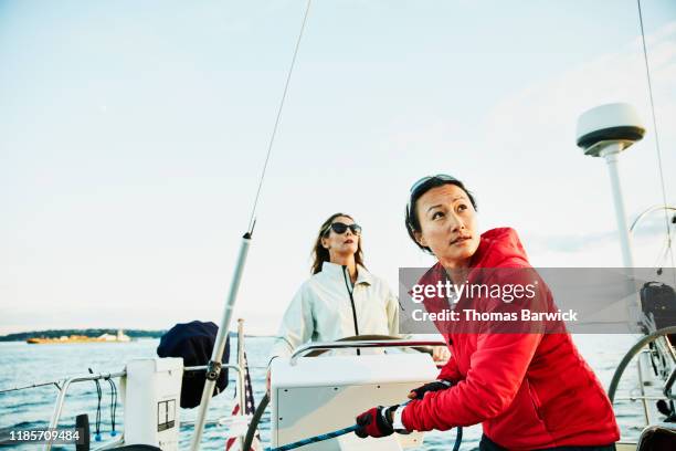 female sailor trimming sail during race on summer evening - セーリング ストックフォトと画像