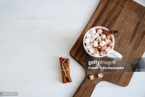 top view mugs with hot chocolate and marshmallows on chopping board near cinnamon. - chocolate top view stock-fotos und bilder