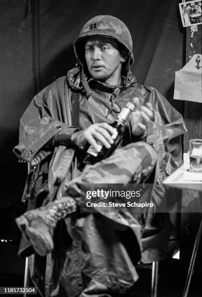 Portrait of American actor Martin Sheen as he unscrews the top of a bottle, seated in a tent on the set of his film, 'Apocalypse Now' , Philippines,...