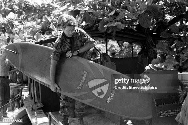 American actor Martin Sheen holds a surfboard as he stands on a river boat on the set of his film, 'Apocalypse Now' , Philippines, 1978.