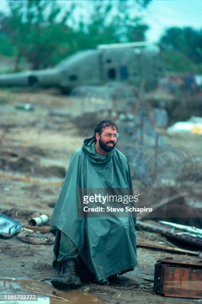 Wrapped in a rain poncho, American film director Francis Ford Coppola sits on the set of his film, 'Apocalypse Now,' Philippines, 1978.