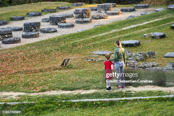 mother and daugther watching the large limestone sanctuary at sarmizegetusa regia archaeological site in hunedoara county, romania, europe. - sarmizegetusa regia stock pictures, royalty-free photos & images