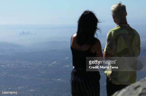 People take in the view with the buildings of downtown Los Angeles partially obscured at midday on November 5, 2019 as seen from Pasadena,...