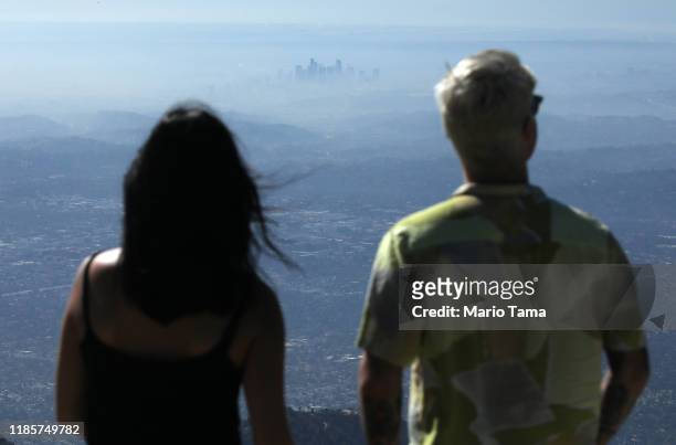 People take in the view with the buildings of downtown Los Angeles partially obscured at midday on November 5, 2019 as seen from Pasadena,...