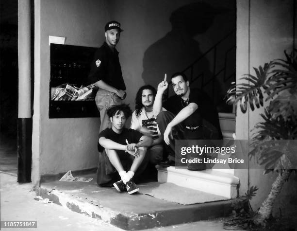 Guitarist Tom Morello , vocalist Zack de la Rocha, drummer Brad Wilk, and bassist Tim Commerford, his forefinger raised, seated on steps outside RATM...