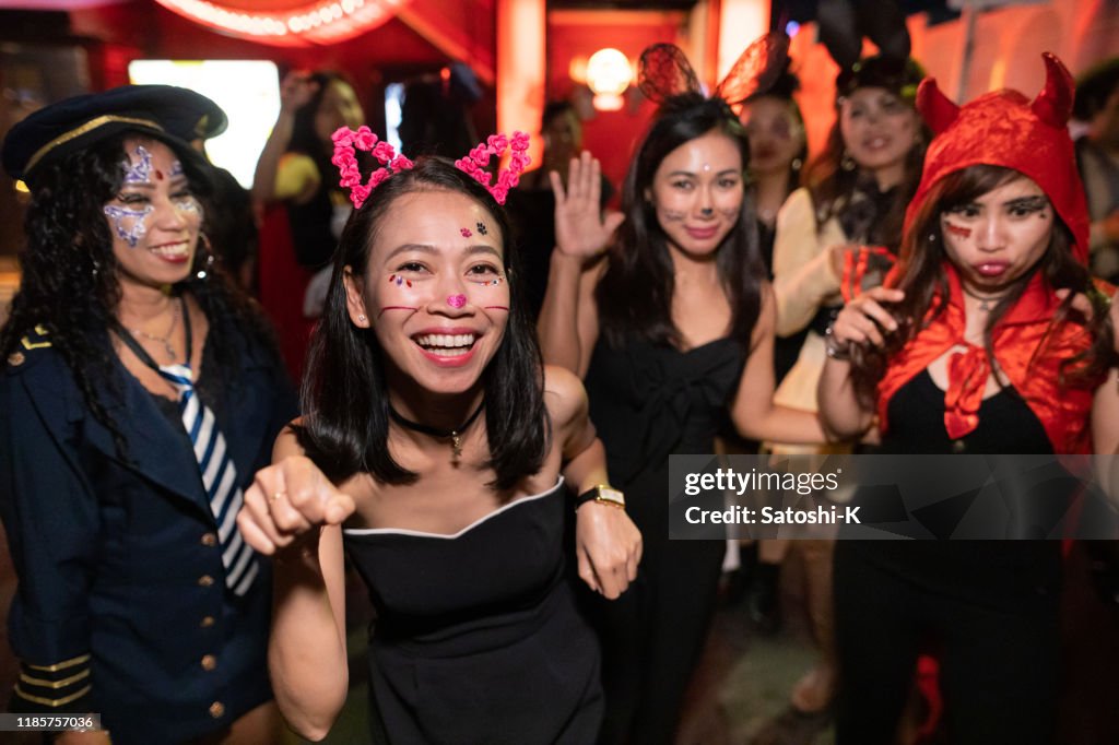 Amigos fêmeas asiáticos no traje de Halloween que anda e que dacing na rua da noite