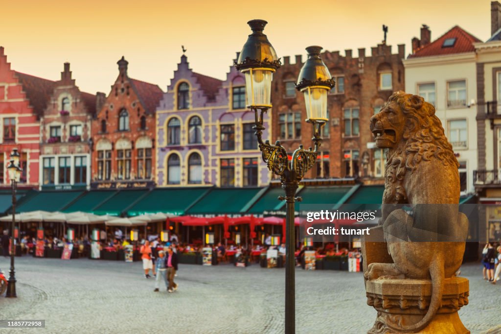 Estatua tradicional del León Belga frente al Ayuntamiento y coloridos edificios de ladrillo en la Plaza del Mercado, Brujas, Bélgica