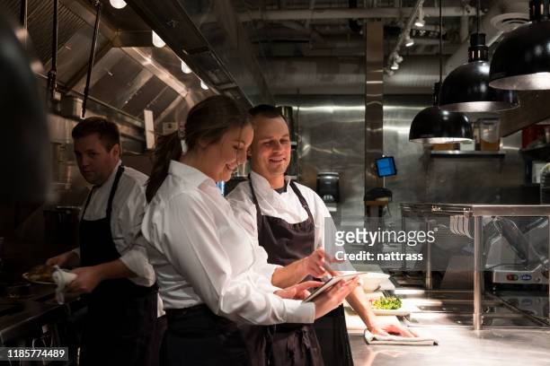 weibliche restaurantleiterin diskutiert menü mit küchenchef - chefs cooking stock-fotos und bilder