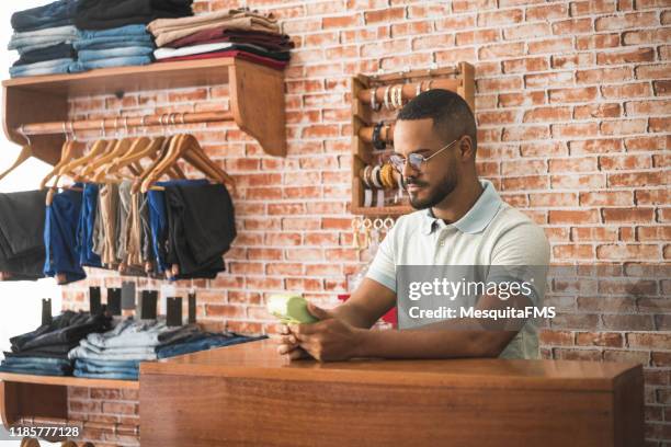 salesman at the checkout in a clothing store - fashion store staff stock pictures, royalty-free photos & images