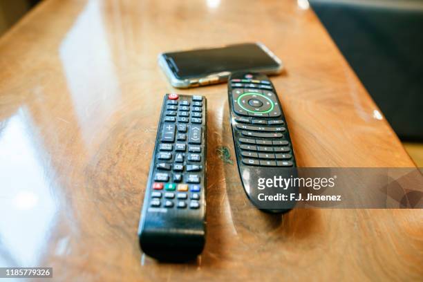 tv remote controls and mobile on table - mobile phone evolution stock-fotos und bilder