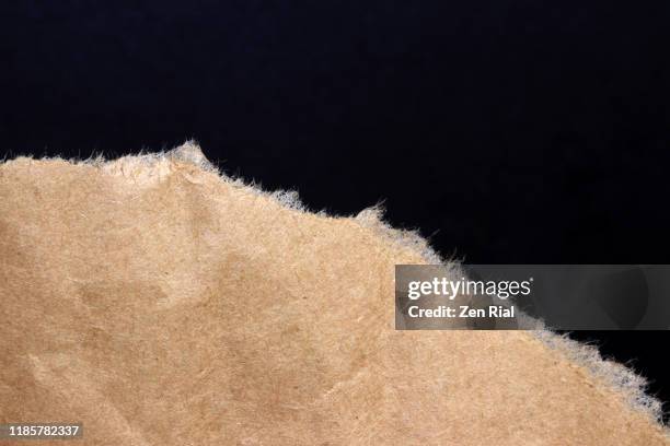 torn brown paper against black background - black craft paper stock pictures, royalty-free photos & images