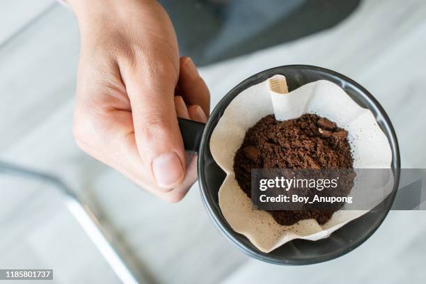 cropped shot view of barista hand holding a cup with ground coffee inside with paper filter before drip it. - filtración fotografías e imágenes de stock