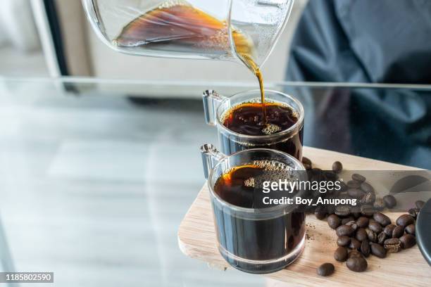 cropped shot of barista pouring a hot coffee after drip in a glass cup of coffee. - black coffee stock pictures, royalty-free photos & images