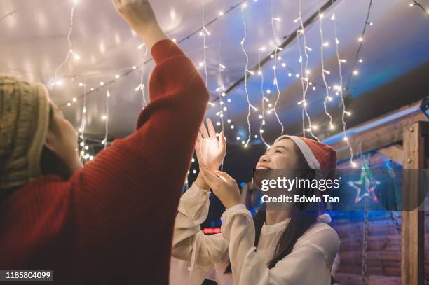 2 chicas asiáticas chinas instalando luz de cuerda de navidad para la fiesta - asian ceiling fotografías e imágenes de stock