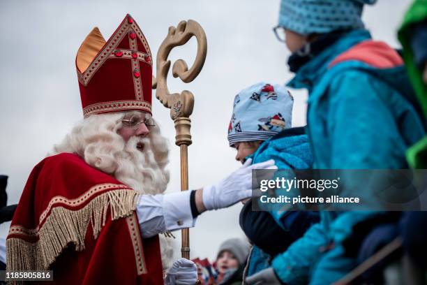 December 2019, North Rhine-Westphalia, Krefeld: Santa Claus greets the waiting children. The Sinterklaas from Venlo arrives with several "Zwarten...