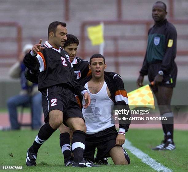 Player of the Iraqi soccer team, Emad Mahoder, shows a shirt with the picture of President Saddam Hussein, as he celebrates with his teammates, his...