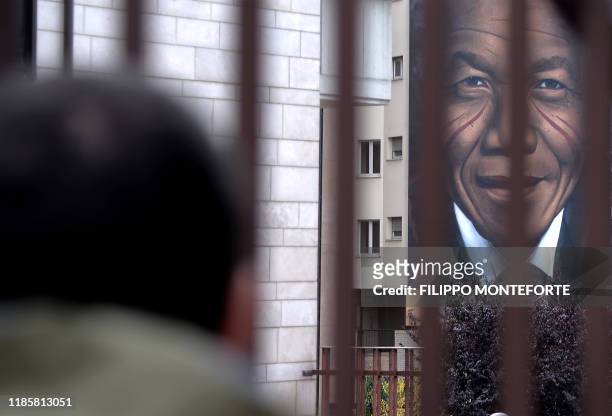 Man looks at a mural by Italian street artist Jorit Agoch, entitlied "Il Condominio dei Diritti" , and depicting late former South African president...