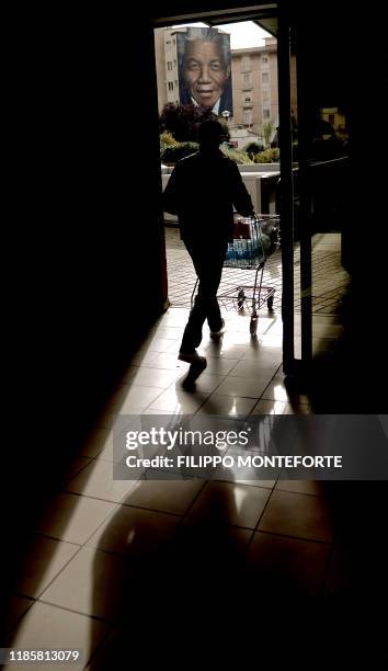 Shopper walks near a mural by Italian street artist Jorit Agoch, entitlied "Il Condominio dei Diritti" , and depicting late former South African...