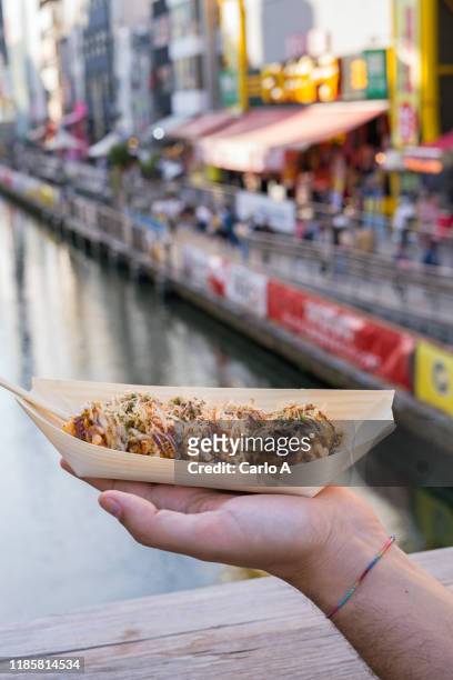 first person view of man eating traditional japanese octopus dumpling balls. - takoyaki stock pictures, royalty-free photos & images