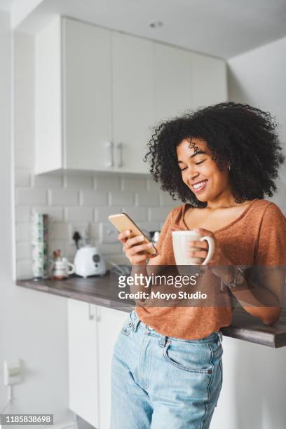 zet de dag aan met koffie en sociale media - woman drinking phone kitchen stockfoto's en -beelden