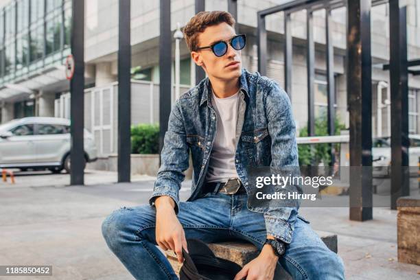 jeune type moderne s'asseyant à l'extérieur - denim photos et images de collection