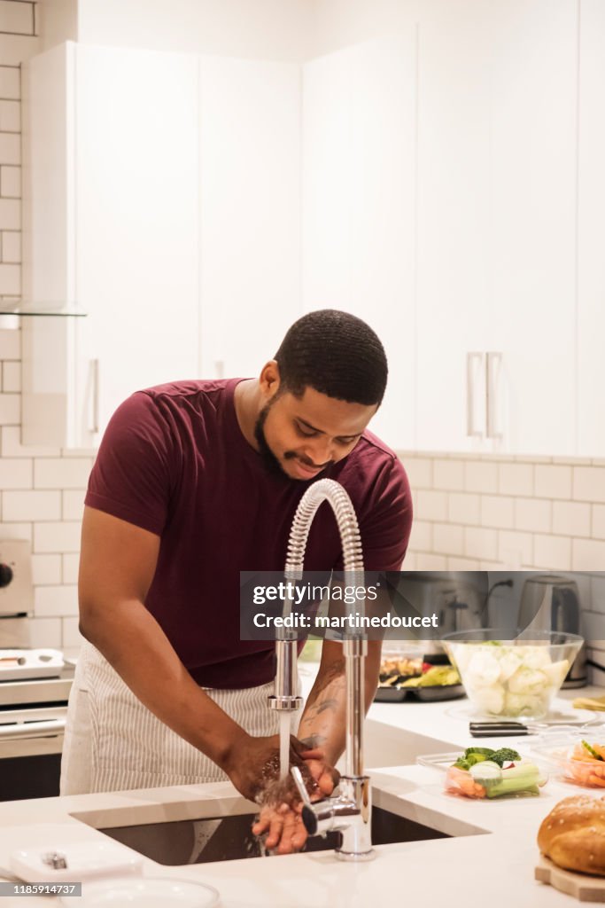 Hombre afroamericano se lava las manos antes de preparar la cena de Acción de Gracias.