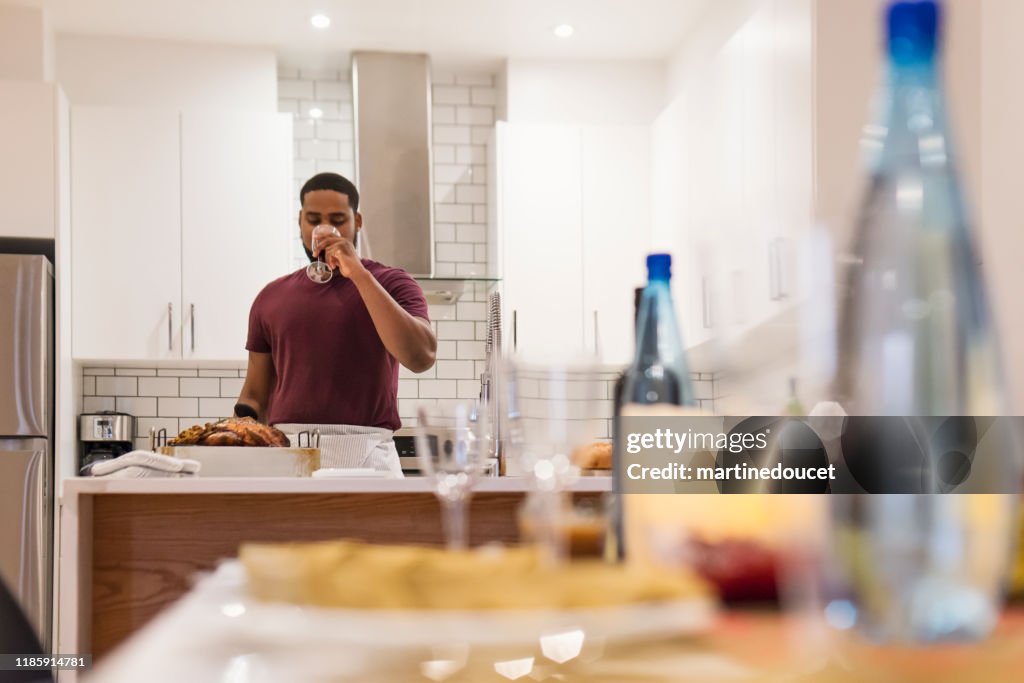African-American having wine preparing Thanksgiving dinner.