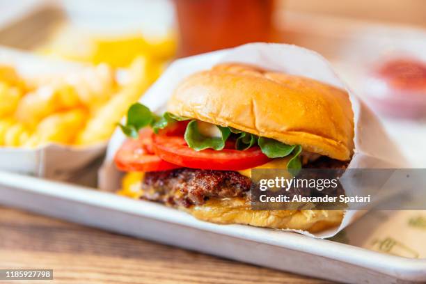 close up of juicy cheeseburger with fresh tomatoes - fast food fotografías e imágenes de stock