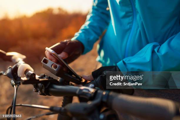 un ciclista de montaña irreconocible que conecta su teléfono a una montura de bicicleta - handlebar fotografías e imágenes de stock