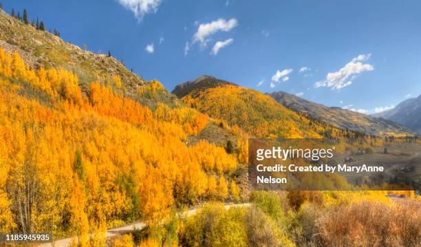 mountain road leading down to colorful valley - farbe ändern stock-fotos und bilder