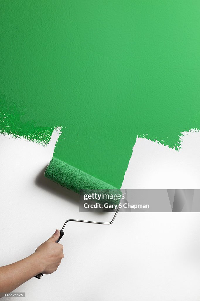 Green paint being rolled onto wall