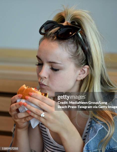 Sydney Grimm bites into a burger at Shake Shack which held family and friends preview of its new restaurant in the 2nd & PCH shopping center in Long...