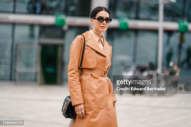 Brittany Xavier wears sunglasses, a brown leather trench coat, a Valentino bag, outside the Sportmax show during Milan Fashion Week Spring/Summer...