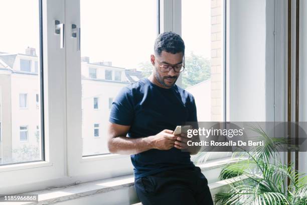 portrait of a young man on the phone indoors - asian man sitting casual imagens e fotografias de stock