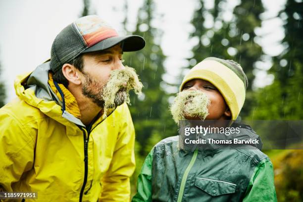 portrait of father and son with mustaches made of moss during camping trip - lampoon foto e immagini stock