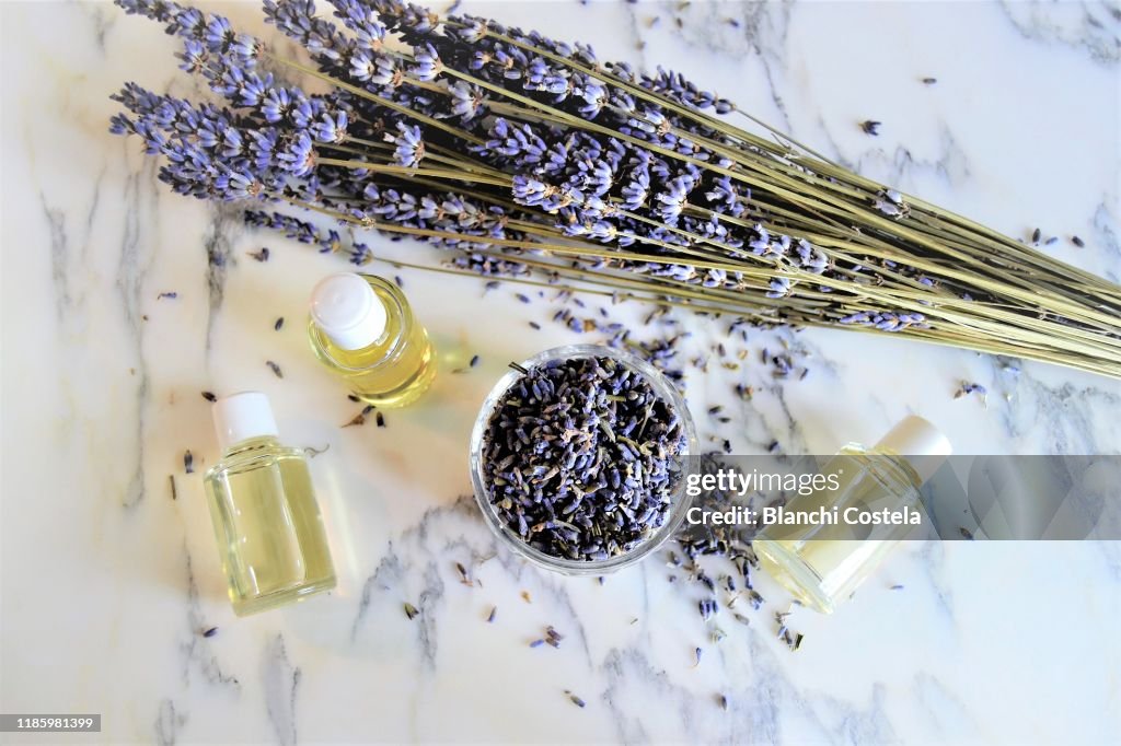 Aromatic oils with lavender flowers on marble background