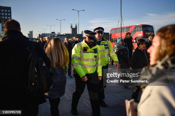 Police officers walk among commuters on London Bridge, after it was reopened following the terror attack, on December 2, 2019 in London, England....