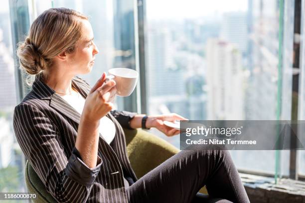 business people, relax and leisure concept. happy smart business woman with cup of tea or coffee at modern office. - leisure work coffee happy stockfoto's en -beelden