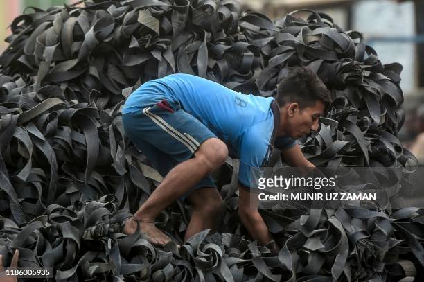 Labourer loads pieces of used tyres on a truck in Dhaka on December 2, 2019.