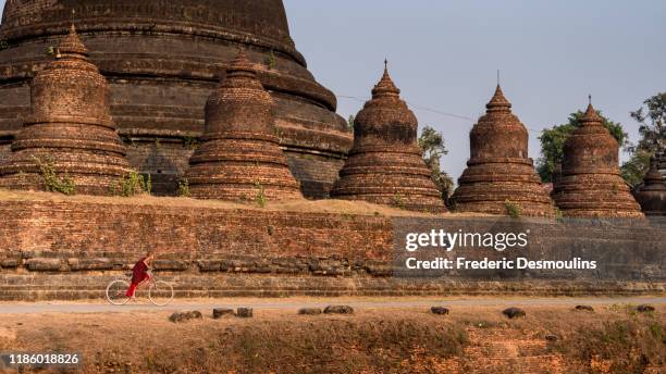 young monk riding a bike at ratanabon pagoda - カラダン川 ストックフォトと画像