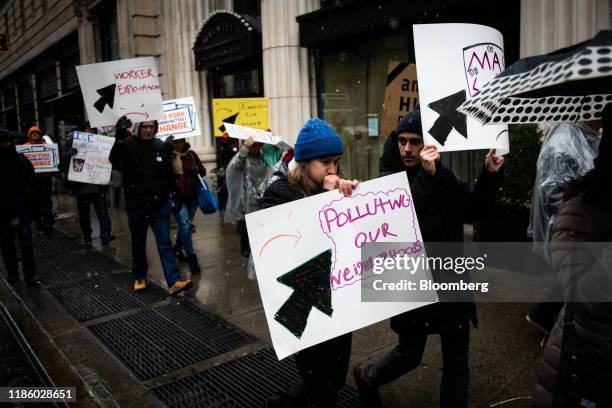 Demonstrators hold signs while marching towards the penthouse of Jeff Bezos, founder and chief executive officer of Amazon.Com Inc., during a protest...