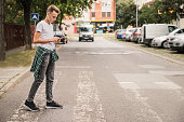 Kid crossing the street at a pedestrian crossing and listening to music on his cellphone