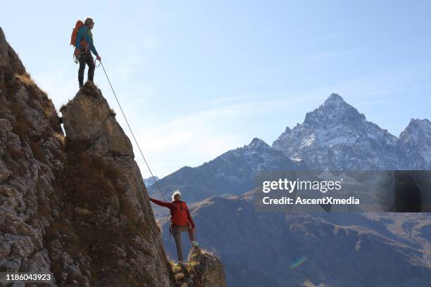 mountaineers ascend to mountain summit, pause to enjoy view - holiday blue sky stock pictures, royalty-free photos & images