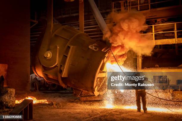 steelworker cleaning pouring end of flask during steel pour in steelworks - steel stock-fotos und bilder